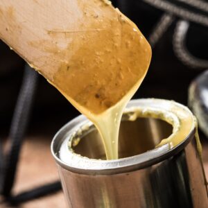 person using a paddle to stir adhesive in a can