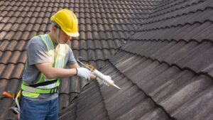 Roofer adding adhesive to a shingle