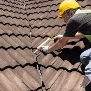 Roofer adding adhesive to a shingle